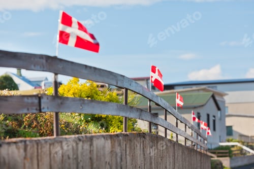 Preview: Danish flags in a row on a wooden fence in a village