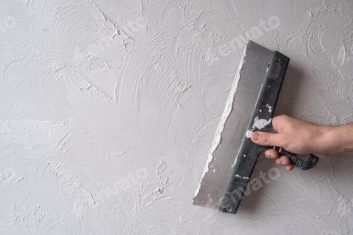 Preview: Hand holding Spatula Smoothing Plaster on Wall