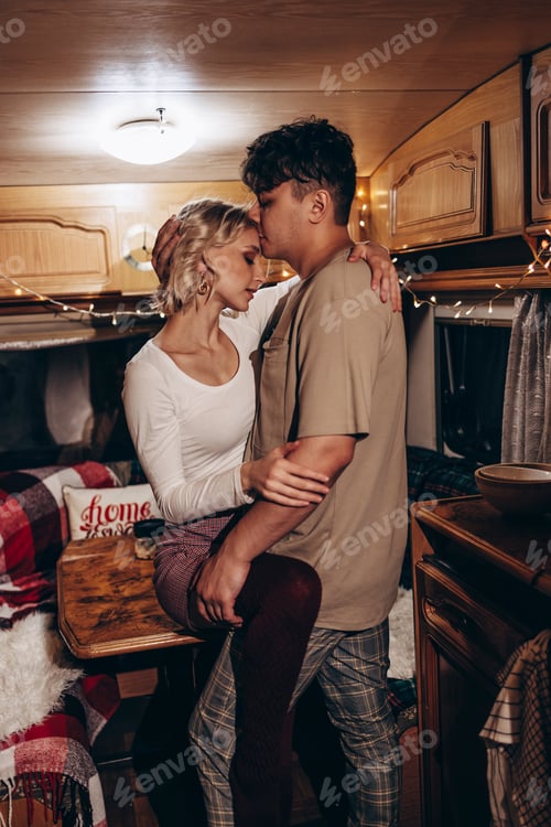Preview: couple in love having fun together in Christmas decorated kitchen in evening, young man and woman ne