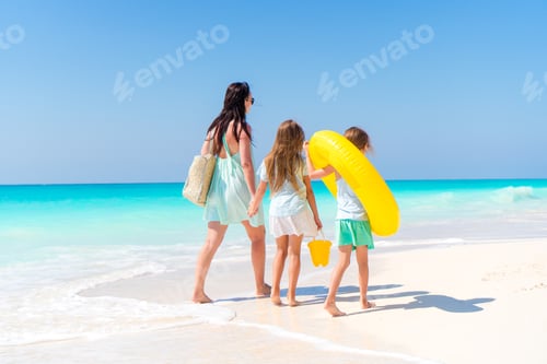 Preview: Adorable little girls and young mother on white beach