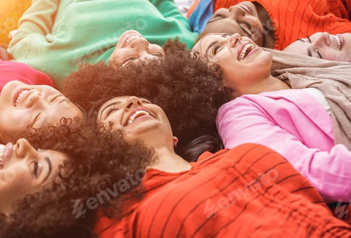 Preview: Happy diverse female friends having fun lying together in circle outdoor