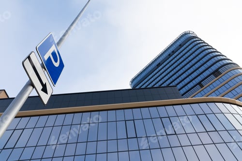 Preview: glass facade of office modern building with parking sign, sharpness on a road sign