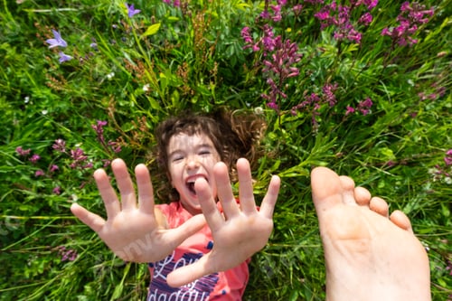 Preview: Portrait of a child girl in summer lying in the grass and wildflowers with heels and palms. summer t