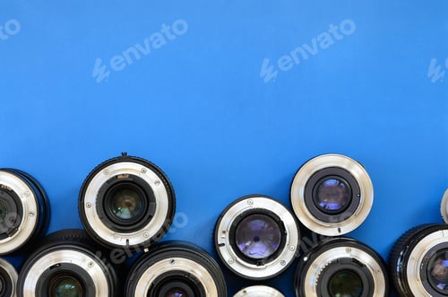 Preview: Several photographic lenses lie on a bright blue background. Space for text