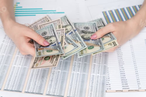 Preview: american dollars in female hands on the background of a desk with business documents