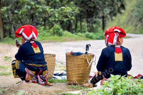 Preview: Vietnamese hill tribe women waiting at the side of dirt road in the countryside using mobile phone