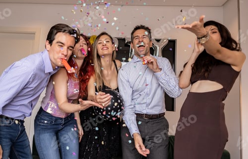 Visualização: Grupo de jovens amigos adultos soprando confetes, aplaudindo e comemorando uma festa