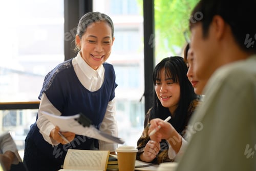 Preview: Friendly middle age lecturer assisting students in classroom. Education concept