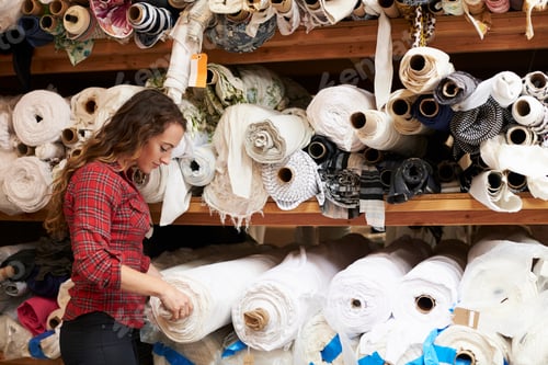 Preview: Young white woman selects fabric at a clothing design studio