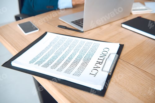 Preview: cropped shot of businessman at workplace with laptop and contract in office