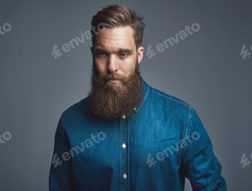 Preview: Pensive young bearded man standing against a gray background