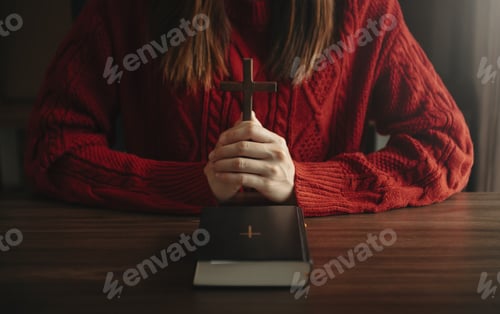 Preview: Woman sitting and studying the scriptures.The wooden cross in the hands.