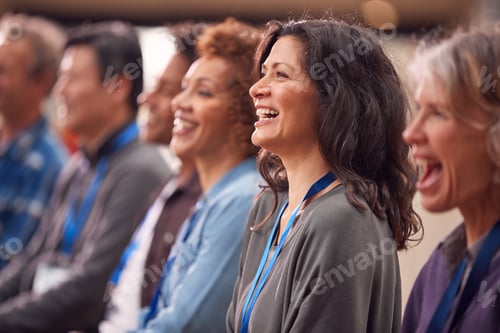 Visualização: Grupo de empresários e empresárias vestidos casualmente ouvindo apresentação em conferência