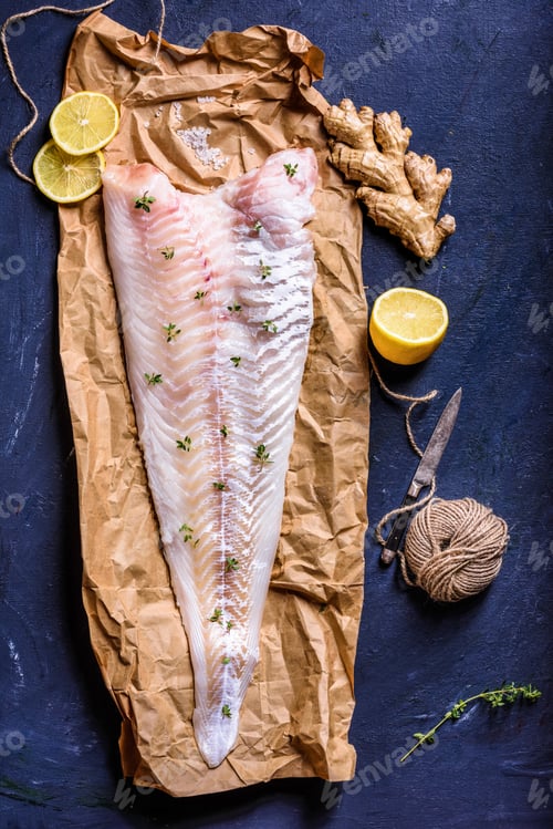 Preview: top view of healthy raw fish with lemon, ginger, rope and knife on blue