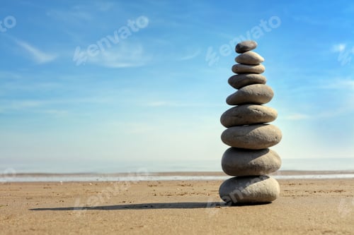 Preview: Balanced Rocks Stacked on Sandy Beach Under Blue Sky