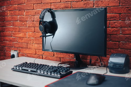 Preview: computer headphones keyboard mouse on table on brick background at home