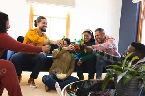 Preview: Happy diverse male and female friends talking, eating popcorn and drinking beer at home