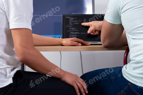 Preview: Two unknown programmers discuss the code that one of them is pointing to on the monitor.