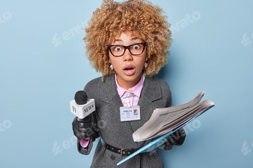 Preview: Surprised curly haired female journalist prepares speech for audience holds microphone and