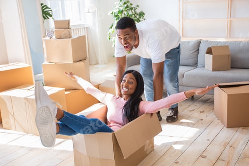 Preview: Moving day fun. Millennial newlywed black couple being silly and playful in their new house, riding