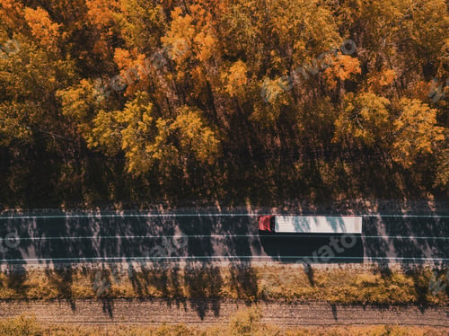Preview: Aerial view of truck on road through forest in autumn