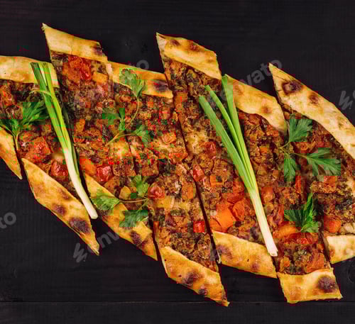 Preview: Turkish pide with minced meat and vegetables lying on black wooden table