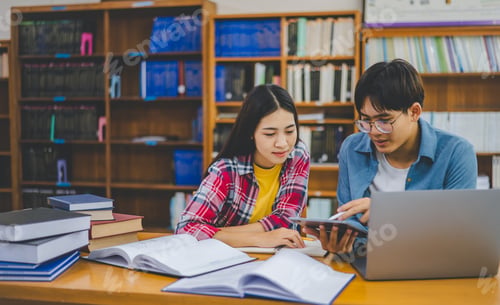 Preview: Students are consulting each other working on laptops and searching for books to study