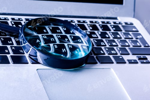 Preview: Magnifying glass rests on keyboard of laptop during work or study session