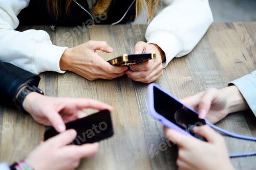 Preview: Hands of three women with the phone on the table