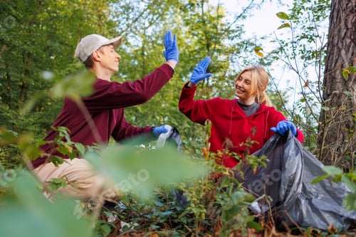Preview: Man and woman high-five each other while cleaning the forest from garbage waste