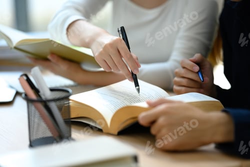 Preview: Close up of university students collaborating on studying material in library