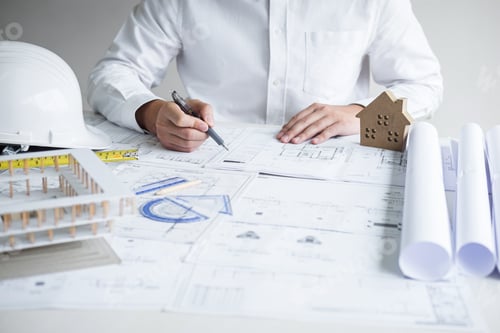 Architect Drafting Building Plans with Scale Model