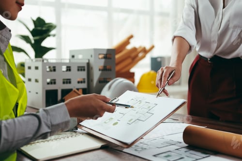 Preview: Architects analyzing blueprints and discussing building project in office