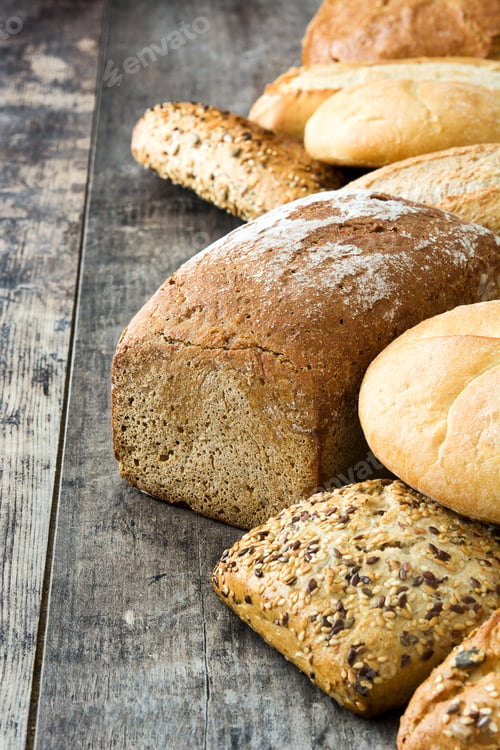 Preview: Different types of bread forming a row on rustic wooden table