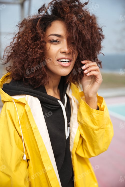 Preview: Amazing african curly young woman wearing yellow coat