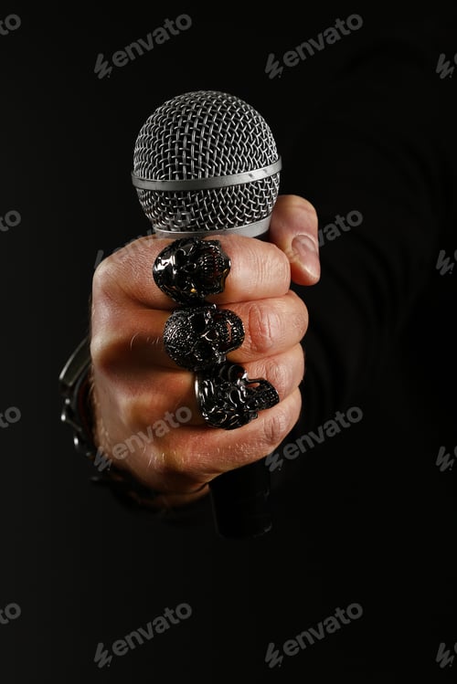Preview: Man hand with microphone isolated on black