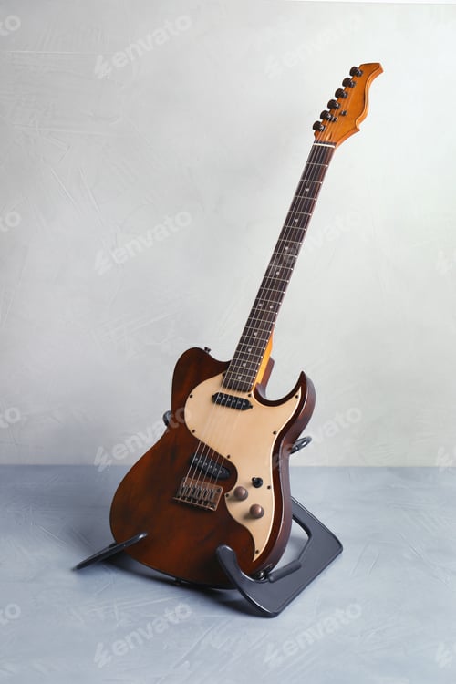Preview: Modern electric guitar on stand near color wall