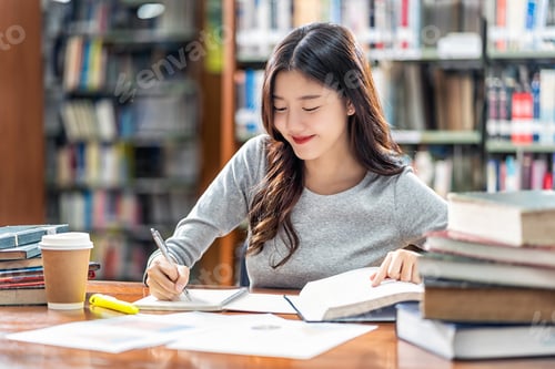 Preview: Asian young Student in casual suit reading and doing homework in library of university