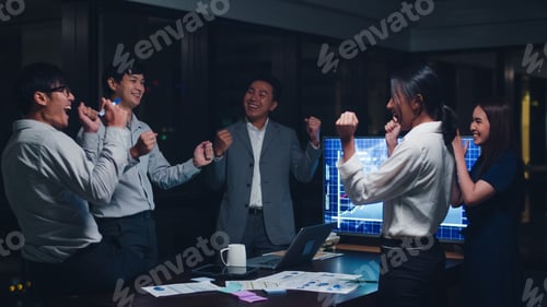 Preview: Millennial group of young businesspeople celebrate giving five after dealing at night office.