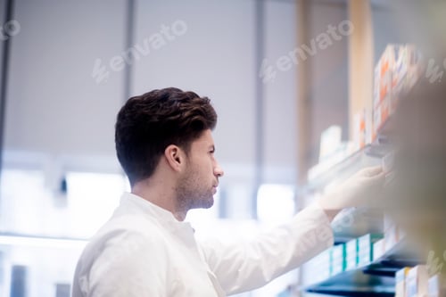 Preview: Young man restocking shelves in a bright store