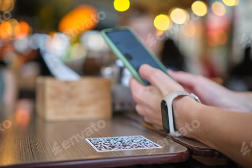 Preview: Closeup of guest hand ordering meal in restaurant while scanning qr code with mobile phone for