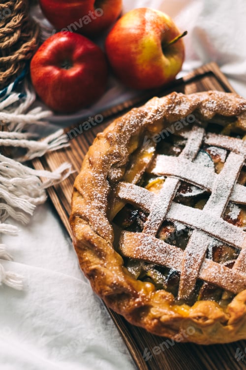 Preview: Homemade apple pie on a wooden board with cinnamon and a golden crust.