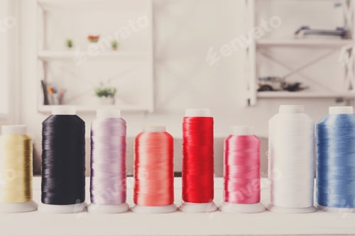 Preview: Colorful thread spools on wooden table close up