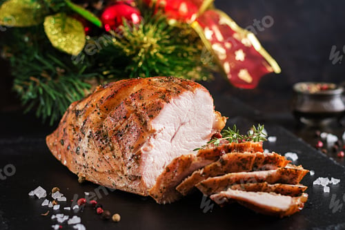Preview: Roasted sliced Christmas ham of turkey on dark rustic background. Festival food.