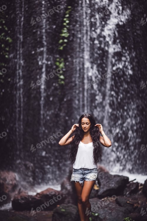 Preview: Beautiful brunette woman enjoying near waterfall