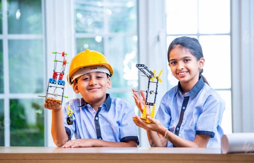 Preview: Indian Students in uniform hard hats study crane mechanism with 3D model during classroom activity
