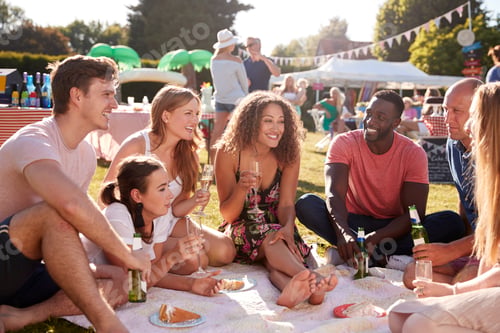 Preview: Group Of Friends Sitting On Rug At Summer Garden Fete With Drinks