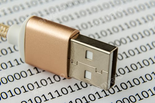 Preview: Closeup shot of a USB cable on a piece of paper with numbers and codes written on it