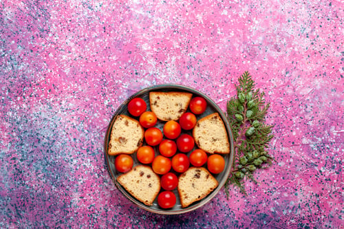Preview: top view delicious sliced cake with sour fresh plums inside pan on pink background pie sweet sugar