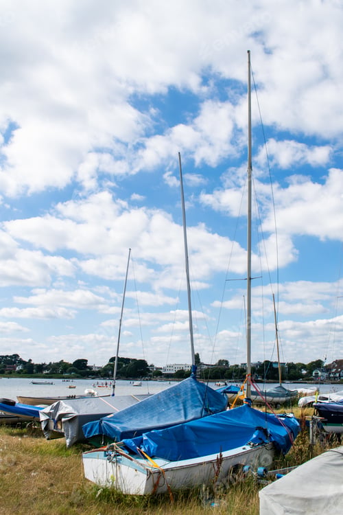 Preview: Small sailing or fishing boats on land with masts and covers on in Mudeford Quay
